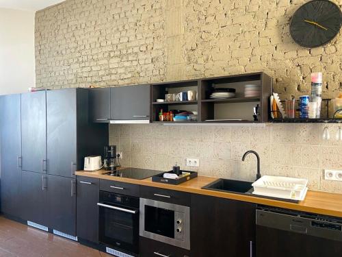 una cocina con fregadero y un reloj en la pared en Maison standing 9 chambres 5SB avec extérieur, en Roubaix