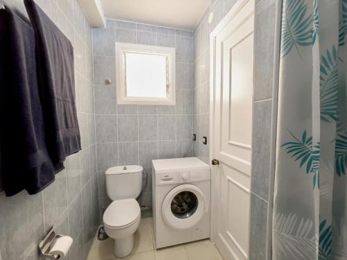 a bathroom with a toilet and a washing machine at Matorral Beach Apartament beautiful ocean view in Morro del Jable