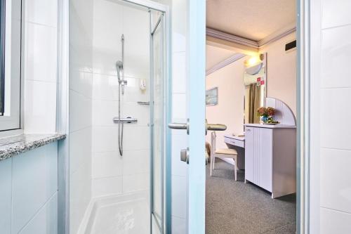 uma casa de banho com um chuveiro e um lavatório. em Hotel Plavi Plava Laguna em Porec