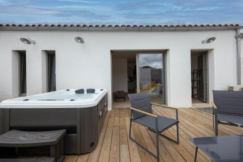 une baignoire assise sur une terrasse avec des chaises dans l'établissement Un cocon climatisé avec jacuzzi, à Marsilly