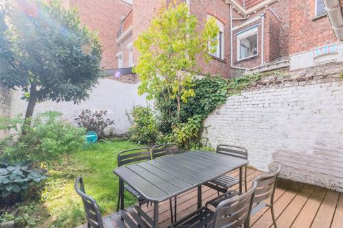 a table and chairs on a patio with a brick wall at 3 bedroom house with garden, near Lille in La Madeleine