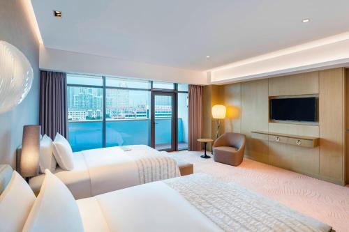 Habitación de hotel con 2 camas y TV de pantalla plana. en Le Meridien Qingdao West Coast Resort en Huangdao
