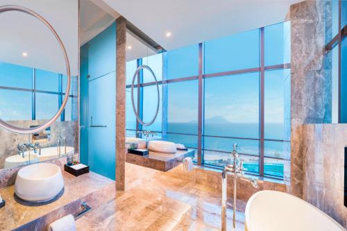 a bathroom with two sinks and two mirrors at Le Meridien Qingdao West Coast Resort in Huangdao