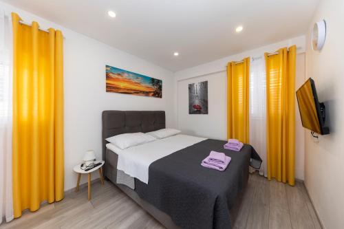 - une chambre avec un lit et des rideaux jaunes dans l'établissement Family apartments Zadar, à Zadar