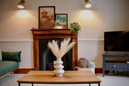 un soggiorno con camino e un tavolo con un vaso di Luxurious cottage with cosy fireplace in Matlock a Winster