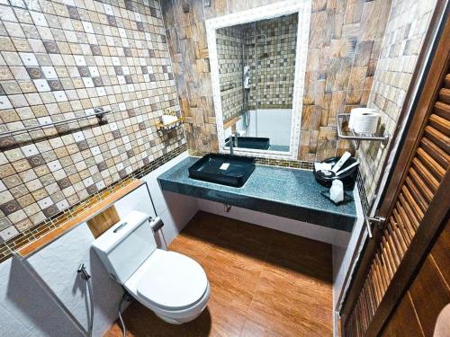 y baño con aseo y lavabo con espejo. en โรงแรมเชียงใหม่ล้านนา & โมเดิร์นลอฟท์ (Chiangmai Lanna Modern Loft Hotel), en San Kamphaeng