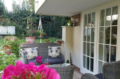 a patio with a wicker chair and a table with flowers at Cristina’s flat Riccione in Riccione