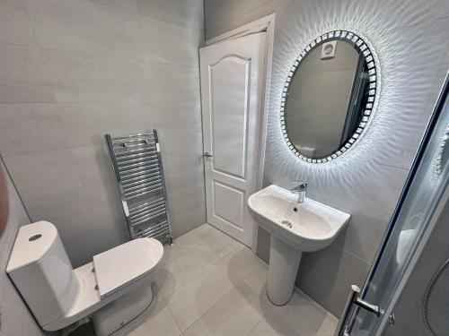 a bathroom with a toilet and a sink and a mirror at Modernised 4 Bedroom House close to city Centre, Kep Stays in Leeds