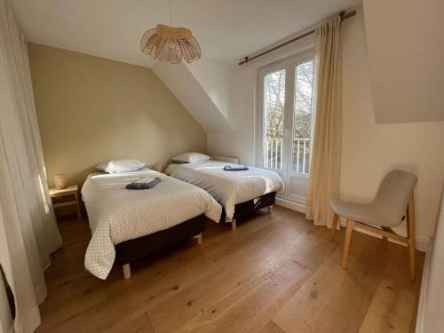 two beds in a room with a window and a chair at Maison Touquet pour 4 personnes in Le Touquet-Paris-Plage