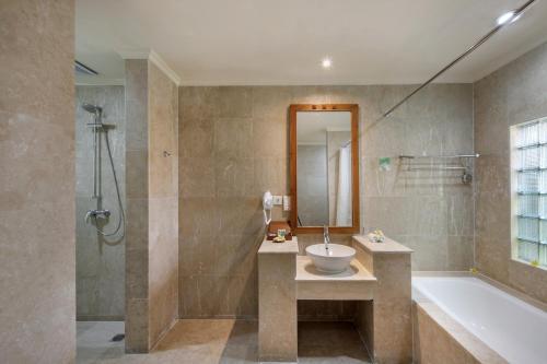 庫塔的住宿－伊斯坦納拉瑪大酒店，浴室配有水槽、淋浴和浴缸。