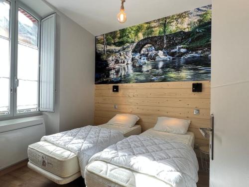 two beds in a room with a painting on the wall at Joli T3 rénové ds une villa 1900 in Cauterets