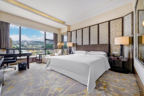 a bedroom with a large white bed and a desk at Sheraton Zhongshan Hotel in Zhongshan