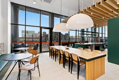 a dining room with tables and chairs and large windows at Switch Living in the Centre of Adelaide in Adelaide