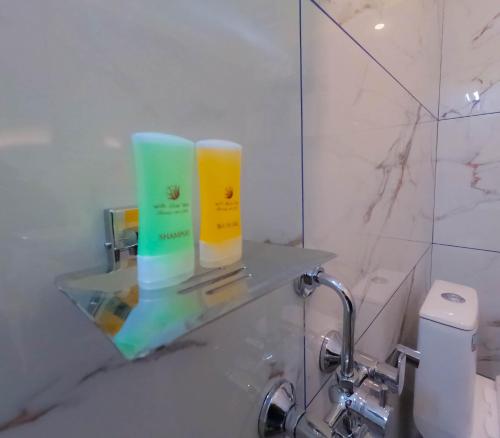 a bathroom with two bottles of soap on a glass shelf at A S Manzil Lounge in Trivandrum