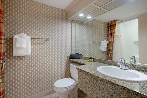 a bathroom with a white toilet and a sink at Best Western PLUS Port O'Call Hotel in Calgary