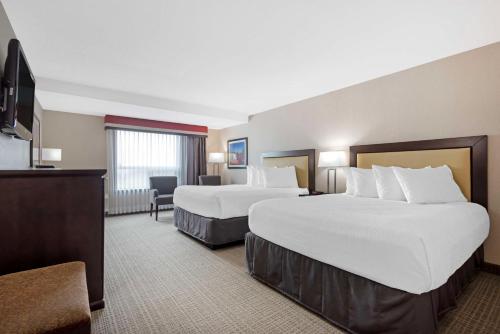 a hotel room with two beds and a television at Best Western PLUS Port O'Call Hotel in Calgary