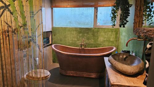 een badkamer met een koperen bad en een wastafel bij Villa in the forrest of Amsterdam with Pool in Velsen-Zuid