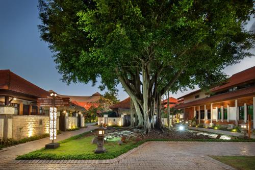 a courtyard with a tree and some buildings at Grand Istana Rama Hotel in Kuta