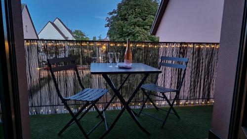 - une table et des chaises sur un balcon avec une bouteille de vin dans l'établissement Le Cosy des Marronniers - 6 Pers, à Sélestat