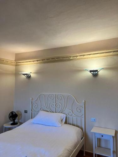 a bedroom with a white bed with two lights on the wall at Borgo BiancoMatilde - Locanda in Monchio di Sarzano