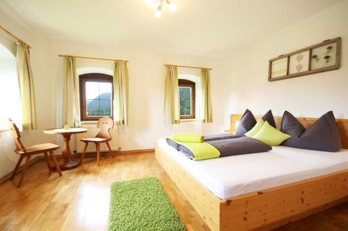 a bedroom with a bed and a table and windows at Almliesl BREI-708 in Breitenbach am Inn