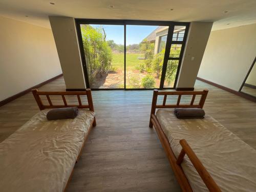 two beds in a room with a large window at Eids Farm in Mmukubyane