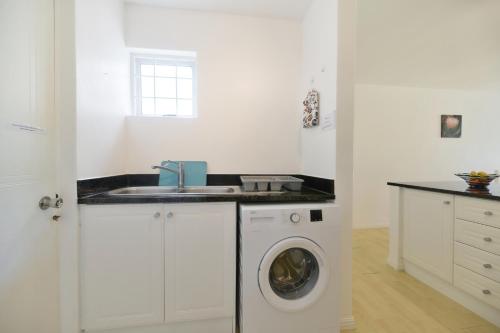 a white kitchen with a washing machine and a sink at 25 The Tides in Struisbaai