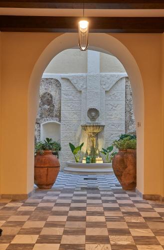 an archway with a fountain in a building with potted plants at Relais - Palazzo Greco Stella in Lamezia Terme
