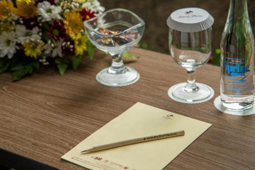 a pen on a table with two glasses and a bottle at Grand Istana Rama Hotel in Kuta