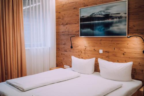 1 cama con sábanas blancas y almohadas en una habitación en Apartment Auenfeld en Schröcken