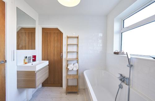 ein Badezimmer mit einer Badewanne, einem Waschbecken und einem Spiegel in der Unterkunft Sunny Days: Beautiful Spacious 4 bed house in Torquay