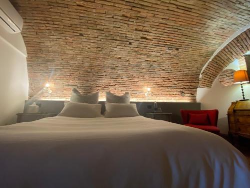 - une chambre avec un grand lit blanc et un mur en briques dans l'établissement B & B Beata Colomba, à Rieti