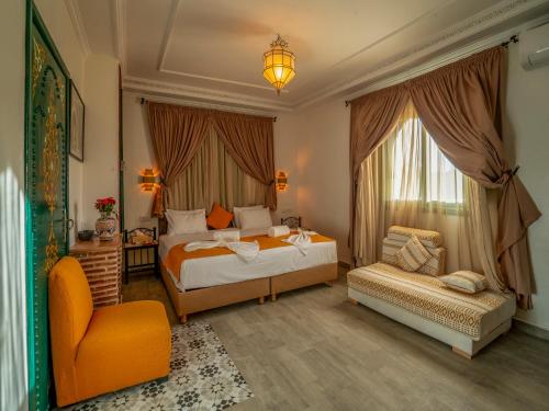 a bedroom with two beds and a chair at Riad Dar Sido in Marrakesh