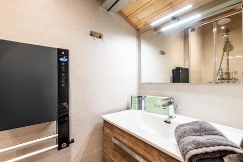 une salle de bain avec un lavabo et un grand miroir dans l'établissement Valgardena, à Morzine