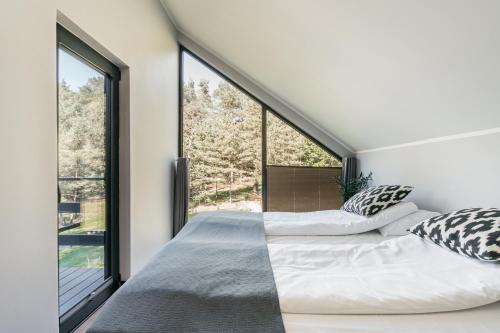 a bedroom with two beds and large windows at Narusa Leśna Przystań in Frombork