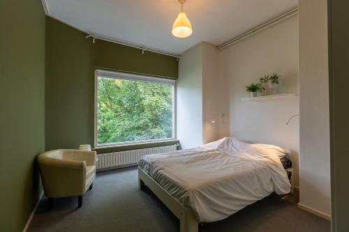 1 dormitorio con cama, ventana y silla en Zeeuwse Kustbunker, en Groede