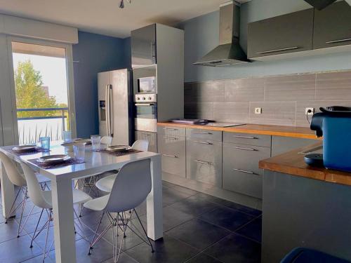 Spacieux T3 Standing Parking privé centre ville Montpellier في مونبلييه: مطبخ مع طاولة بيضاء وكراسي بيضاء