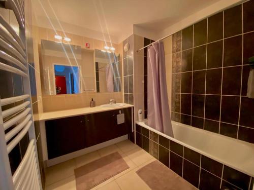 Spacieux T3 Standing Parking privé centre ville Montpellier في مونبلييه: حمام مع حوض وحوض استحمام ومرآة