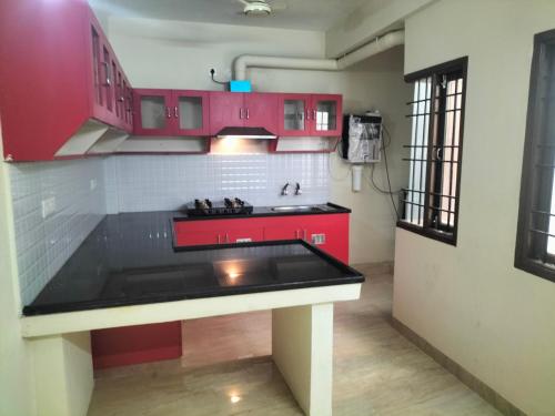 a kitchen with red cabinets and a black counter top at vinoth in Mannārgudi