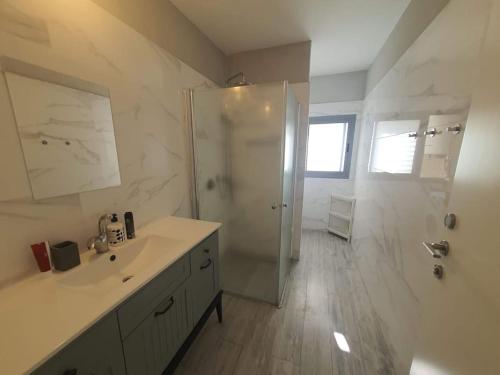 a white bathroom with a shower and a sink at Renovated central 4 bedroom apt with great terrace and Bomb Shelter in Ramat Gan