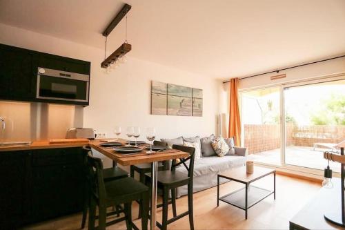 een keuken en een woonkamer met een tafel en een bank bij Le Balmoral - Plage à 1 min - ménage inclus - terrasse lumineuse in Wimereux