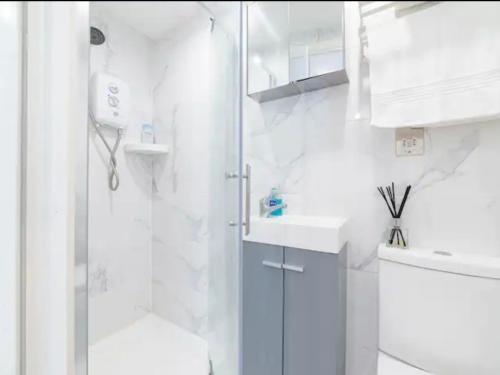 a white bathroom with a shower and a sink at Pass the Keys Cozy Studio just 20 mins to Central London in Raynes Park