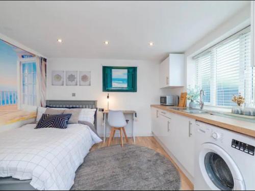 ein Schlafzimmer mit einem Bett, einem Waschbecken und einer Waschmaschine in der Unterkunft Pass the Keys Cozy Studio just 20 mins to Central London in Raynes Park
