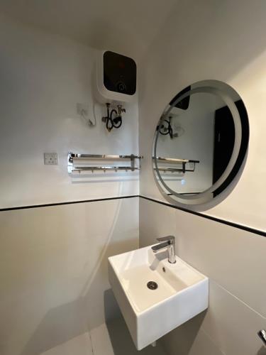 a white bathroom with a sink and a mirror at COC00N by IVY in Lagos