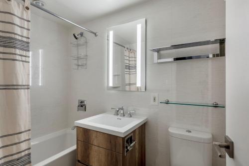 a bathroom with a sink and a toilet and a mirror at Midtown East 2br w elevator nr train NYC-1255 in New York