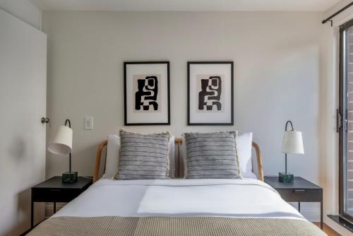 a bedroom with a white bed with two pictures on the wall at Midtown East 2br w elevator nr train NYC-1255 in New York