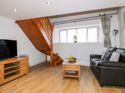 a living room with a black leather couch and a television at The Weary Friar Inn in Pillaton