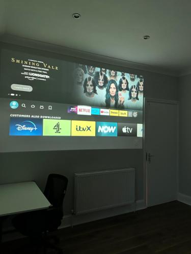 a wall with a large screen with movies on it at Black & White Double Bedroom in London