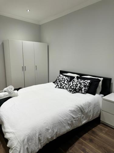 a bedroom with a large bed with white cabinets at Black & White Double Bedroom in London