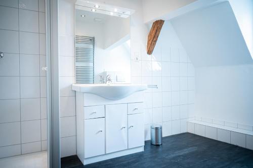 a white bathroom with a sink and a mirror at Ferienhäuser in Ernst